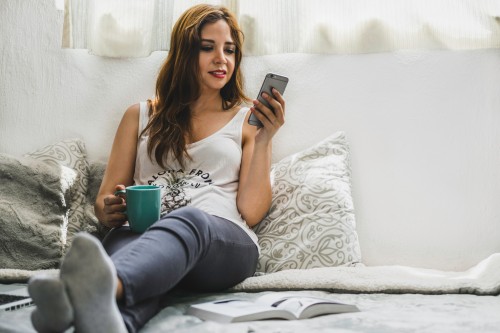 woman holding cup wearing tank top sitting on bed 1125048